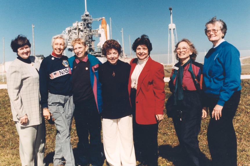 A 1995 photo of Wally Funk and the other six members of the Mercury 13 standing on a launch pad near the Space Shuttle Discovery