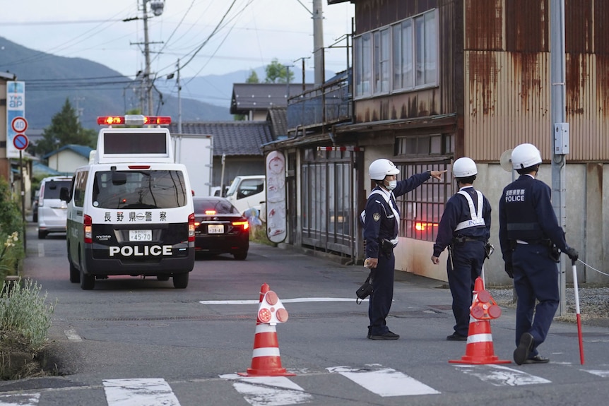 Japanese police officers stand on street.