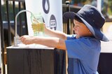 A primary school student fills water bottle from Source hydropanel tap.