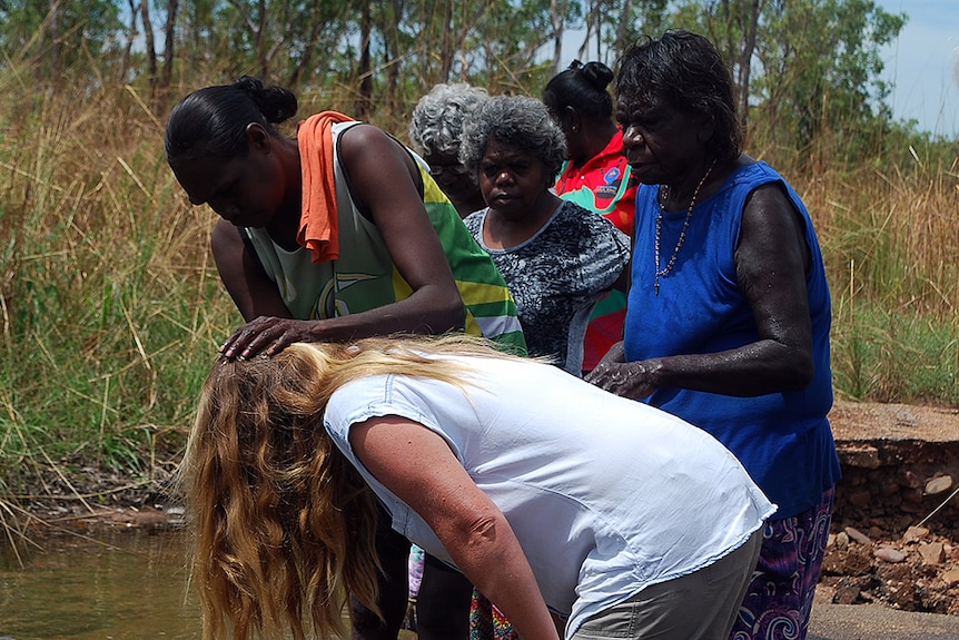 A woman taking part in the Cultural Connection tour in Nauiyu has her head wet.