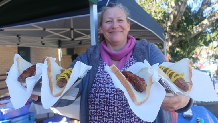 Woman holds four sausages on bread