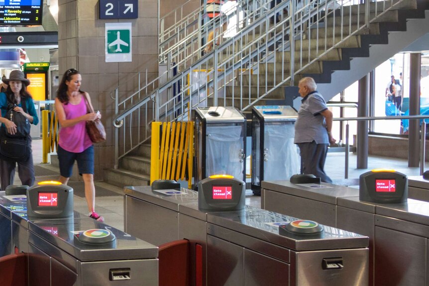Two women walk past see-through bins at Circular Quay train station in Sydney.