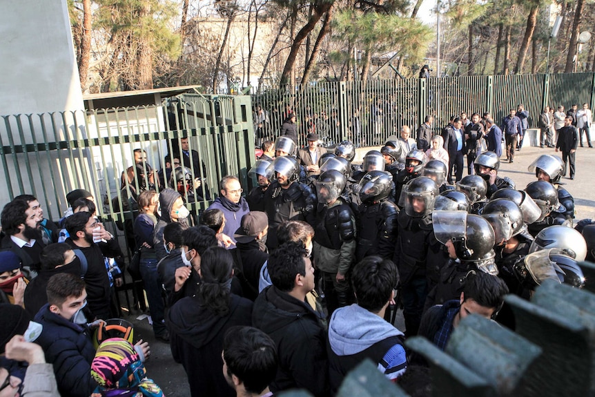 A group of protesters faces off against armoured police.