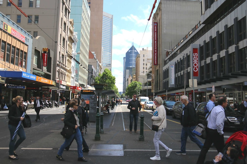 People walk on a pedestrian crossing on Elizabeth Street in Melbourne's CBD.