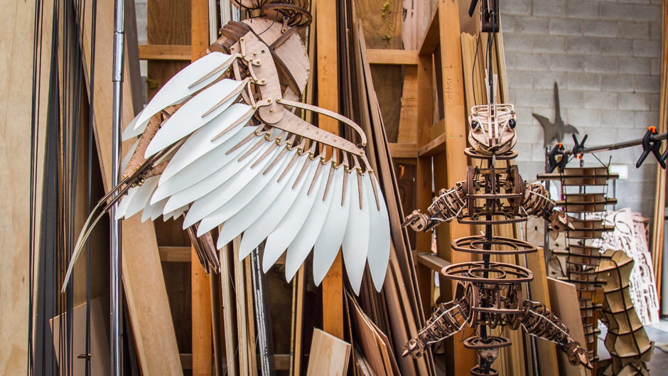 Large wings that extend and move hang alongside a nearly completed puppet.