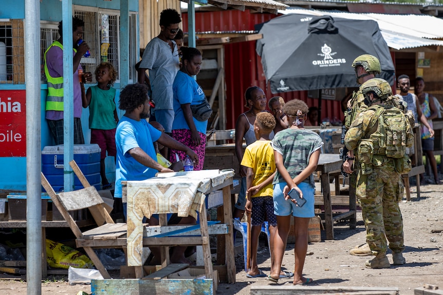 Australian soldiers speak to Solomon Islanders in a street in Honiara.