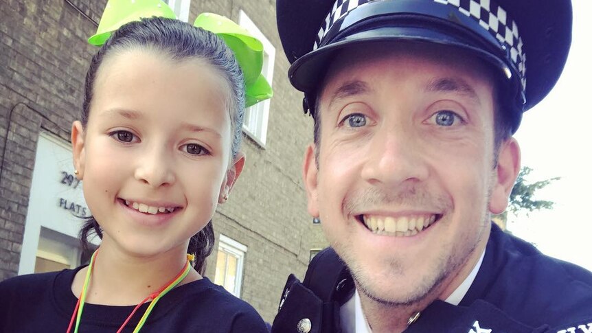 A police officer smiles with a young girl at a multicultural festival. The photo is a tight shot