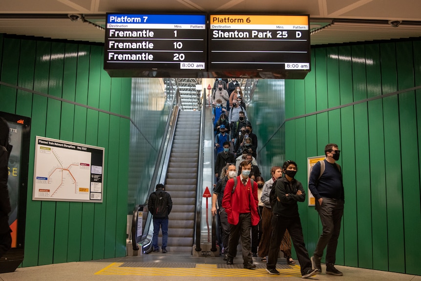 People wearing masks as they come down the escalator in the Perth underground