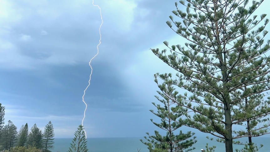 a lightning strike hitting the ocean, photographed from a beach