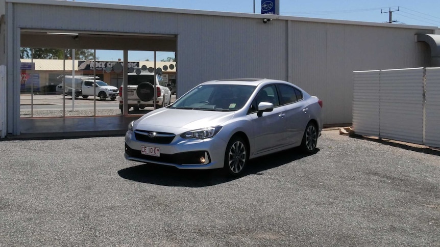 a silver car packed on a car yard