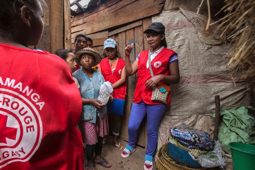 Uniformed Red Cross volunteers speak to villagers.
