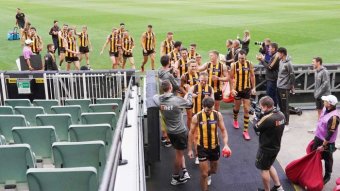 Players walk off an empty stadium after their last game before the suspension of the AFL season.