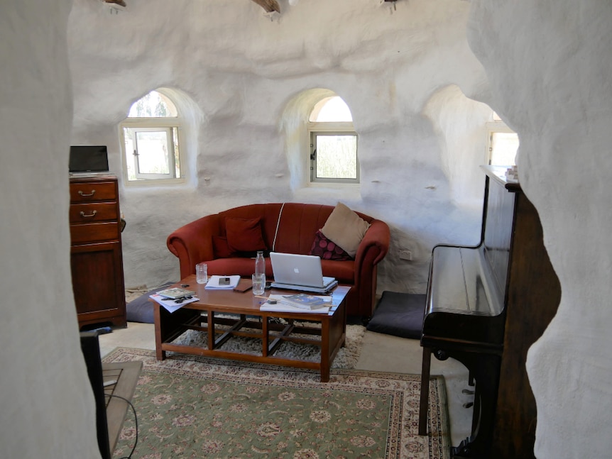 The inside of a room with furniture, white walls and windows.