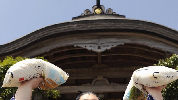 Yamamotoyama poses with rice bags