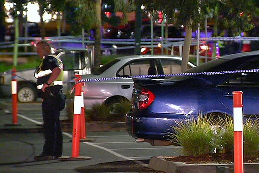 A police officer stands near the scene of a stabbing in a shopping centre car park.