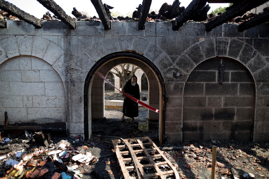 A nun surveys heavy damage at the Church of the Multiplication after a fire broke out in the middle of the night.