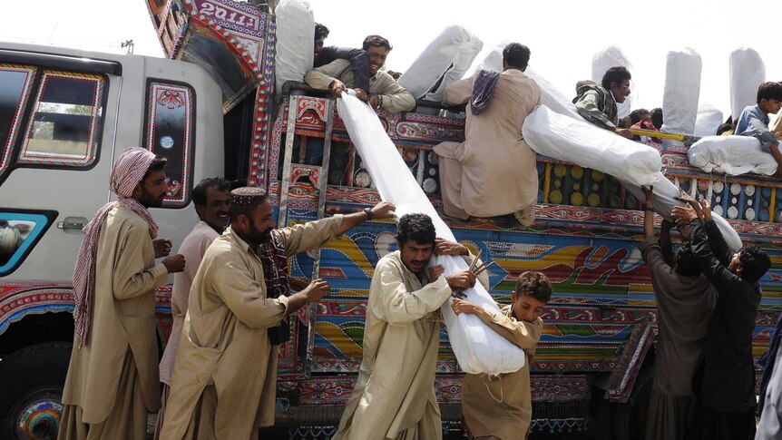 Pakistani earthquake survivors receive tents at a distribution point in the devastated district of Awaran.