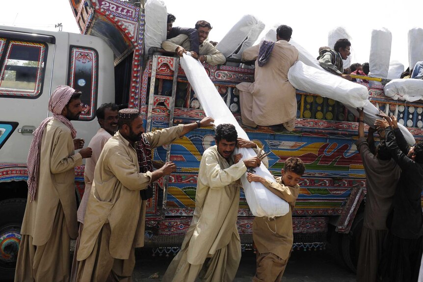 Pakistani earthquake survivors receive tents at a distribution point in the devastated district of Awaran.