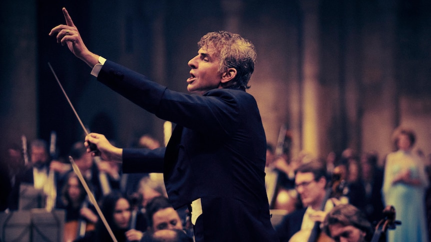 Bradley Cooper in an exuberant pose as conductor Leonard Bernstein in the film Maestro.
