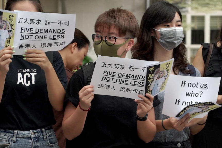 A group of women wearing black t-shirts hold banners.