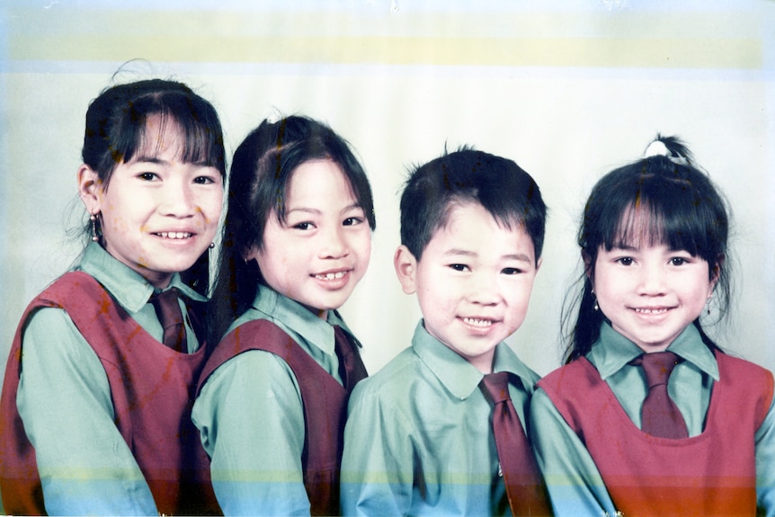 Three young girls and a boy, smiling, wearing school uniforms.
