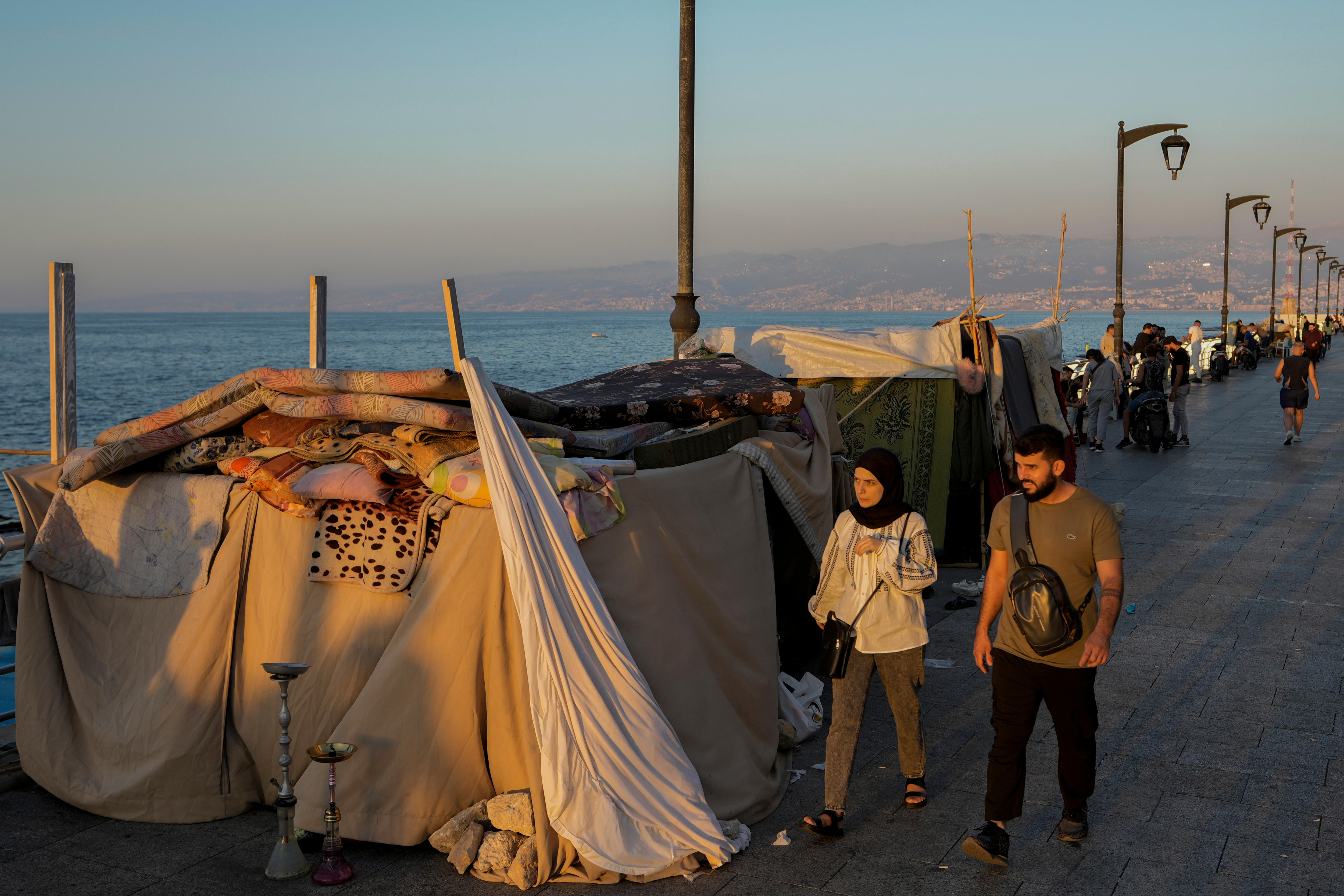 A couple walks past a row of makeshift tens on the waterfront
