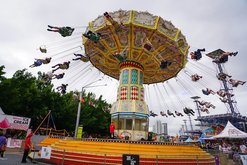 People sit in a carnival ride swing as it spins