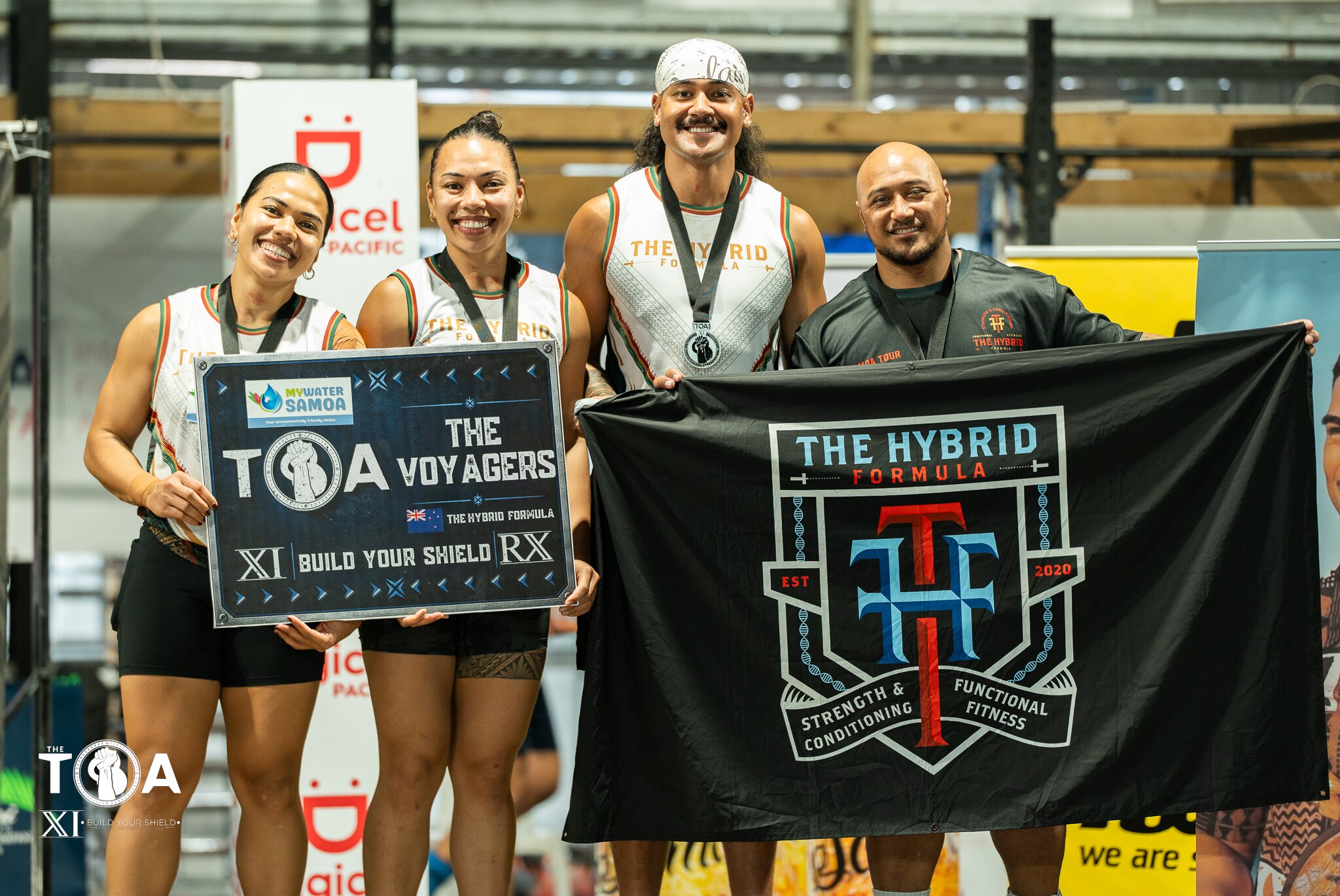 A group of Samoan athletes hold banners and signs while standing on top of a podium during a prizegiving in a gym in Samoa