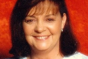 A headshot of a brunette woman wearing a white shirt.