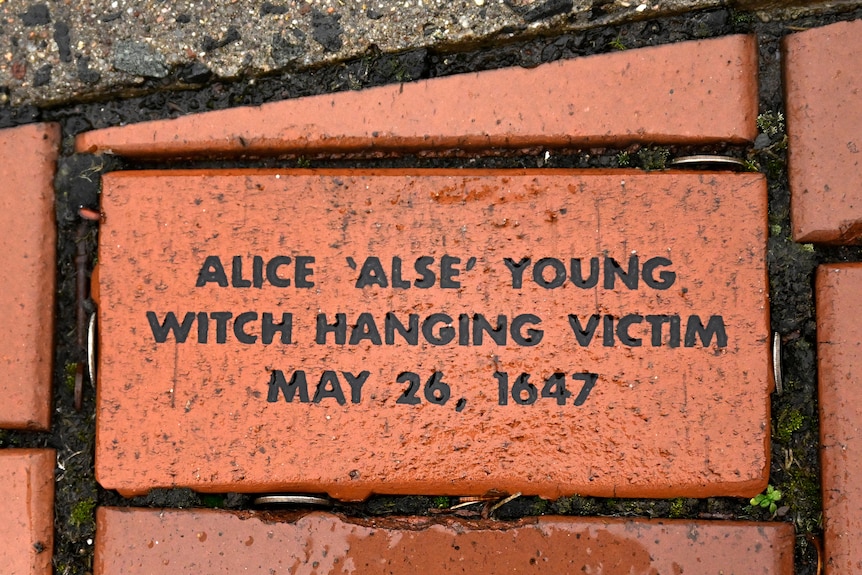 A brick in a wall is inscribed with the name of woman who was hanged for witchcraft in the 1600s