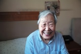 An elderly asian woman smiles at the camera 