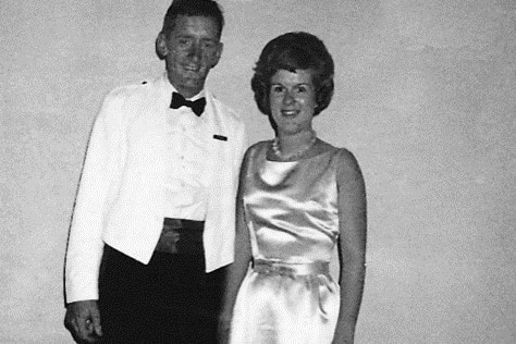 Tim Fischer, wearing a tuxedo, poses for a photo with a woman in a ball gown.