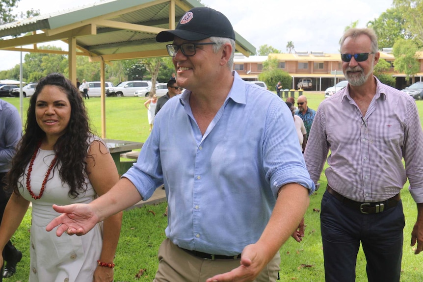 Prime Minister Scott Morrison talk with a few people on the grass in Kakadu National park