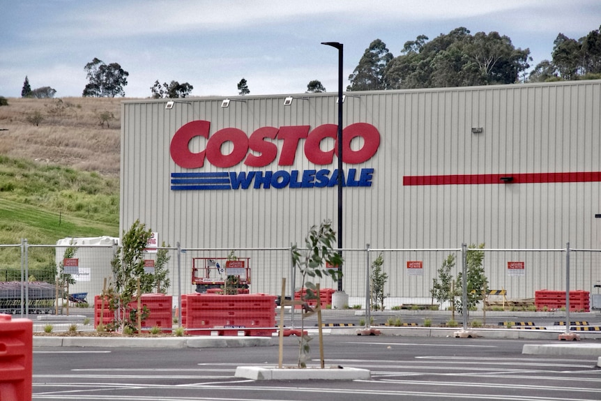 A warehouse building with a large Costco sign on the wall, surrounded by an empty car park.