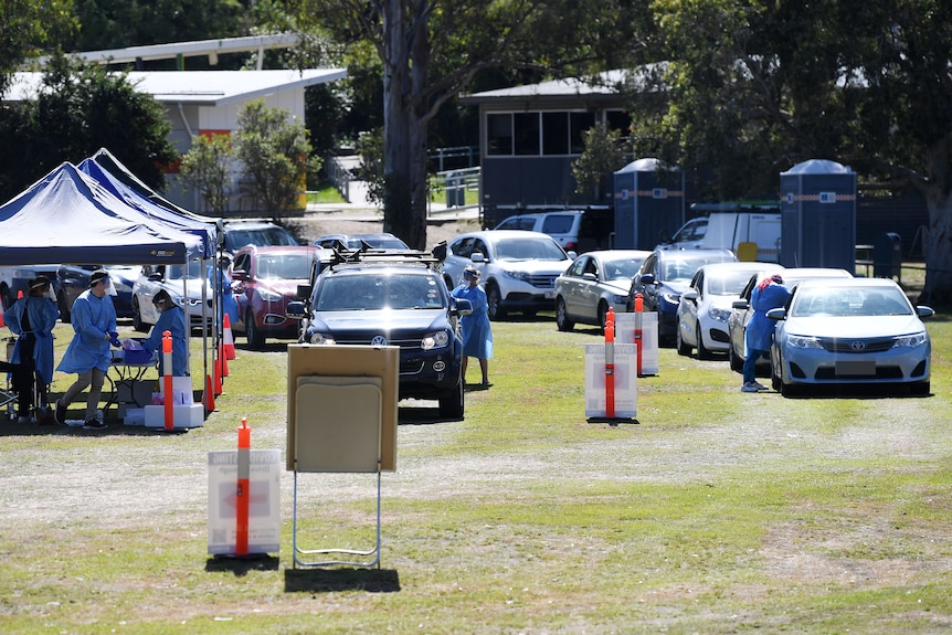 People line up in their cars at a pop-up COVID-19 testing station at Indooroopilly State High School in Brisbane