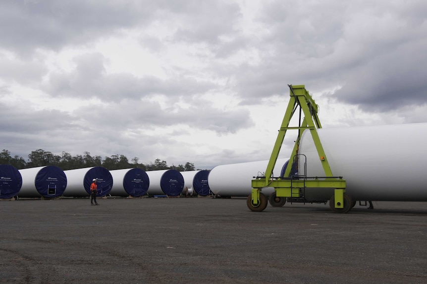 Wind turbine towers being moved in yard.