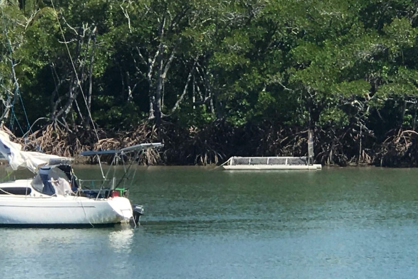 A crocodile trap in place at Dickson Inlet with a small yacht in the foreground.