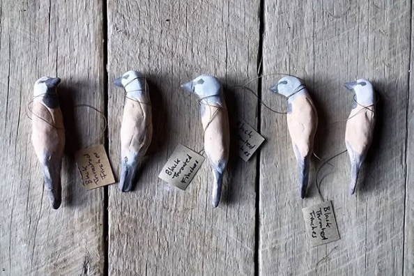 A group of carved black-throated finches with string-tied labels.