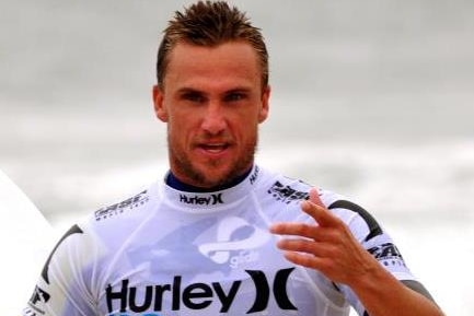 a man holding a surfboard coming out of the surf