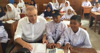 Seorang pria duduk dengan murid sekolah