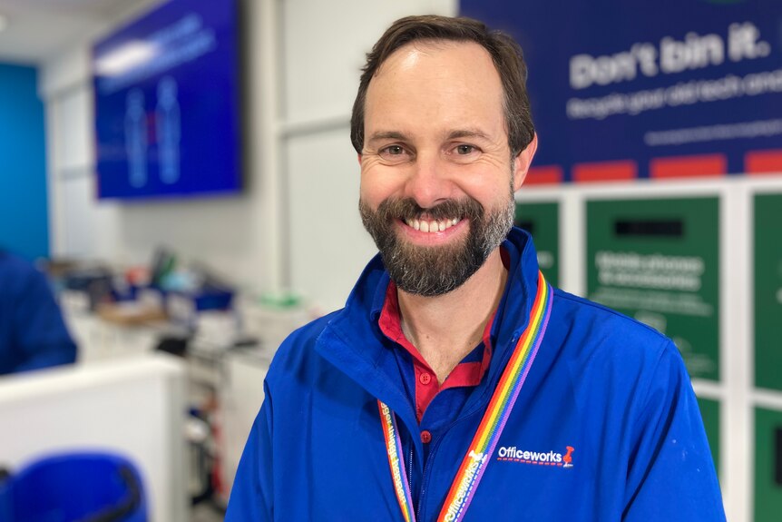 A man with glasses wearing a blue Officeworks branded shirt.