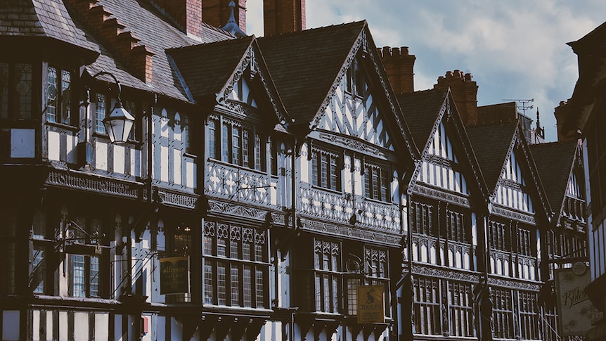 A row of old Elizabethan-style houses in Chester, United Kingdom, with dark wood beams and white walls.