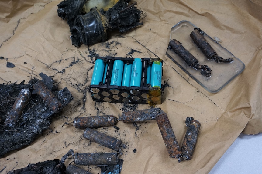 Some unburned rechargeable batteries surrounded by some charred and burnt ones. 