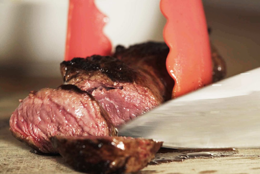 A kangaroo steak being sliced to depict how to cook and enjoy kangaroo, a native Australian ingredient.