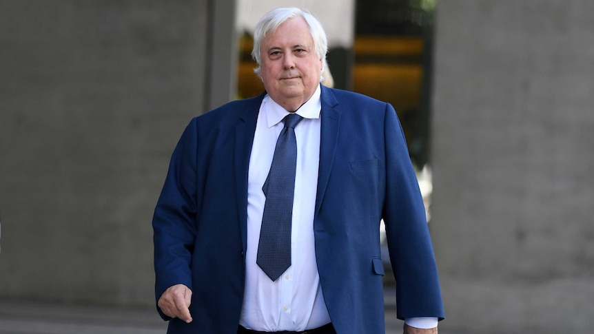Clive Palmer wearing a blue suit and tie and a white shirt leaving a court house.