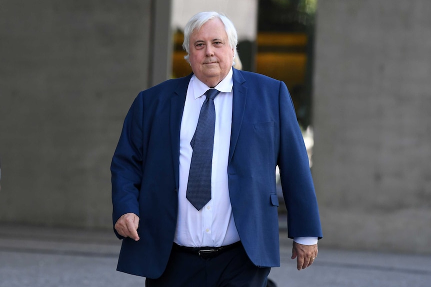 Clive Palmer wearing a blue suit and tie and a white shirt leaving a court house.