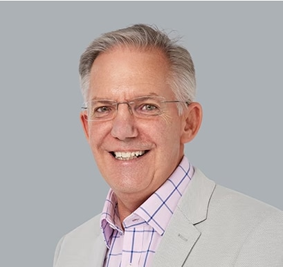 A smiling man in a blazer, with a pink shirt