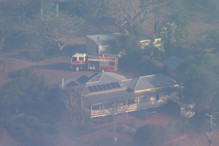 A fire truck parked near a rural home. Smoke creates a haze over the scene
