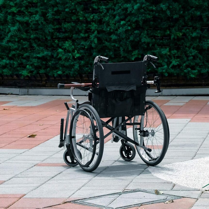 An empty wheelchair with walking stick and railings from a ramp.