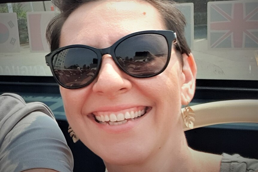Selfie of woman on an open-top bus wearing sunglasses.